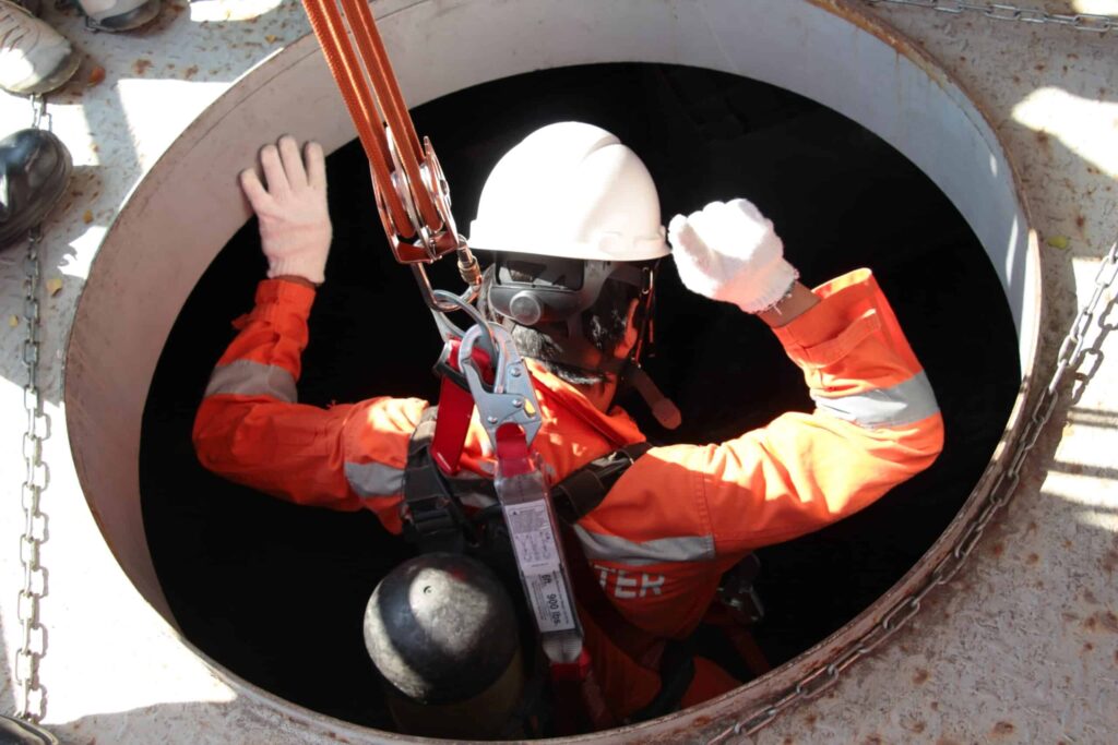 Rescue team performing confined space rescue with specialized equipment in an industrial setting.
