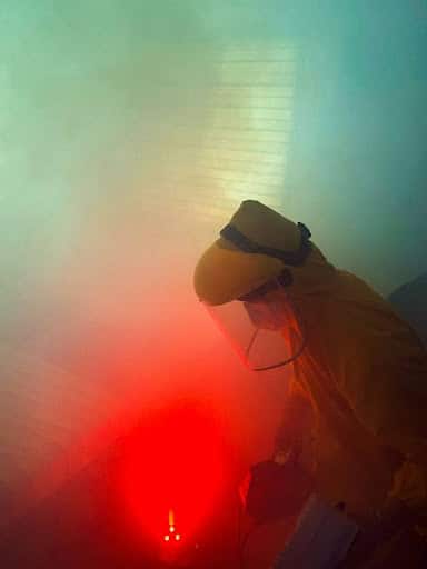 Proper PPE Man in Hazmat suit disposing hazardous items safely.